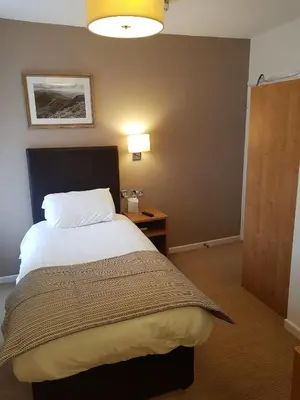 a bedroom with a bed and a lamp and a table at The Wellington in Brecon