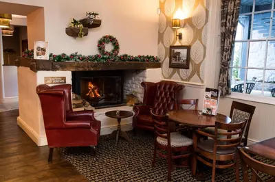 a living room with a fireplace and a table and chairs at The Wellington in Brecon