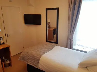 a bedroom with a bed and a mirror and a window at The Wellington in Brecon
