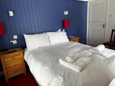 a large white bed with two towels on it at Castle Hotel in Aberaeron