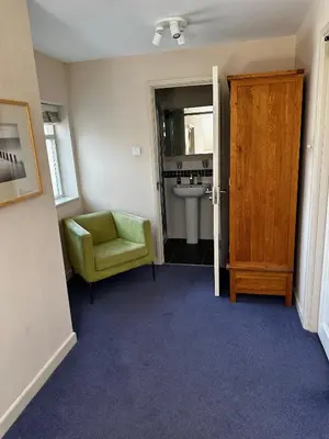 a bathroom with a green chair and a sink at Castle Hotel in Aberaeron