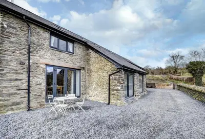a stone cottage with two chairs on a gravel driveway at 2 Bed in Machynlleth oc-bow39 in Darowen
