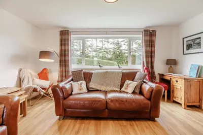 a living room with a brown leather couch and a window at 3 Bed in Bala oc-bow26 in Llanuwchllyn