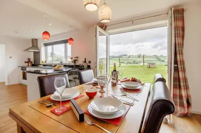a dining room with a wooden table and a kitchen at 3 Bed in Bala oc-bow26 in Llanuwchllyn