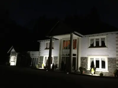 a white house at night with its lights on at Plas Y Dderwen Apartments in Aberystwyth