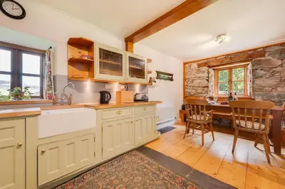 a kitchen with white cabinets and a dining room with a table at 3 Bed in Dolgellau oc-wah569 in Llanfachreth