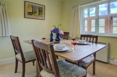 a dining room table and chairs with wine glasses and a vase at 3 Bed in Llangollen oc-waf216 in Glyn-Ceiriog
