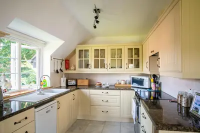 a kitchen with white cabinets and a sink at Berries Coach House in Church Stretton