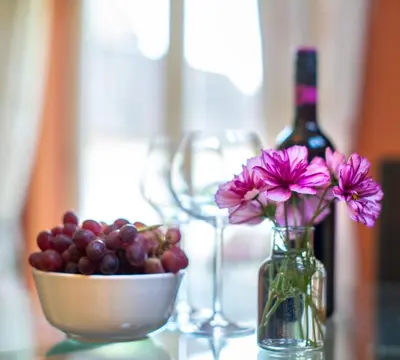 a bowl of grapes and a bottle of wine and a bowl of flowers at Berries Coach House in Church Stretton