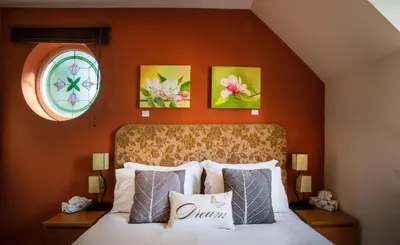 a bedroom with a bed with three paintings on the wall at Berries Coach House in Church Stretton