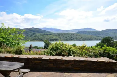 a bench and a view of a lake and mountains at 4 Bed in Barmouth oc-wah585 in Penmaenpool