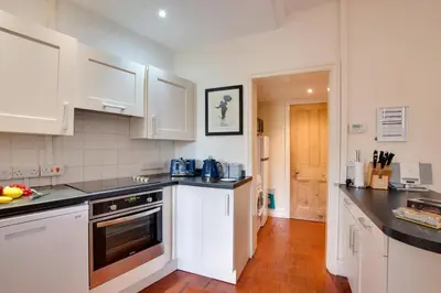a kitchen with white cabinets and black counter tops at 4 Bed in Barmouth oc-wah585 in Penmaenpool