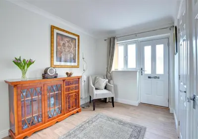 a living room with a wooden dresser and a chair at Tredegar in Dyffryn