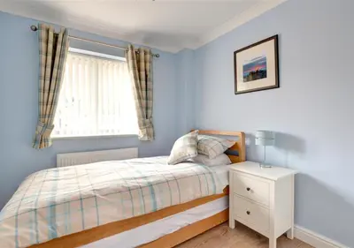 a bedroom with blue walls and a bed and a window at Tredegar in Dyffryn