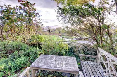 a wooden bench sitting next to a river with trees at 3 Bed in Dolgellau oc-wah484 in Llanfachreth