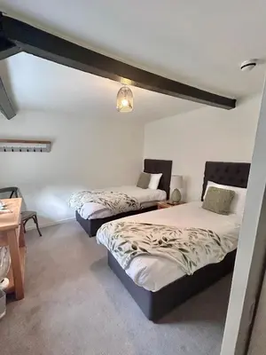 a bedroom with two beds and a table with a lamp at The Beacons Guest House in Brecon