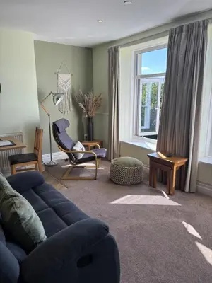 a living room with a blue couch and a window at Bryn Melyn Apartments in Barmouth