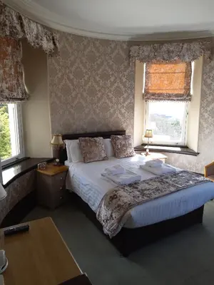 a bedroom with a large bed and two windows at Tyr Graig Castle in Barmouth