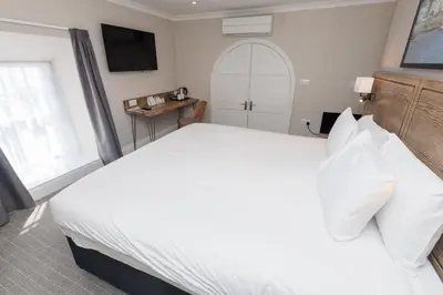 a bedroom with a large white bed and a window at Dovey Inn in Aberdyfi