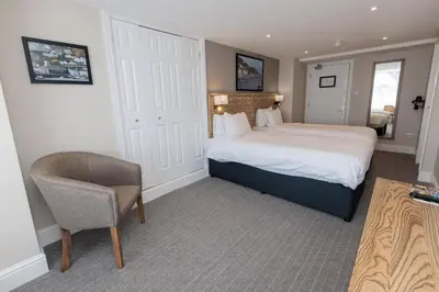 a bedroom with a bed and a chair in a room at Dovey Inn in Aberdyfi
