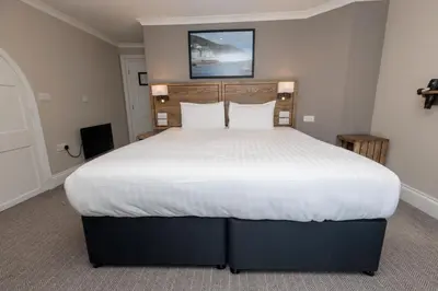 a bedroom with a large bed with white sheets at Dovey Inn in Aberdyfi