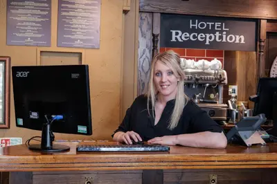 a woman sitting at a desk with a computer at Dovey Inn in Aberdyfi