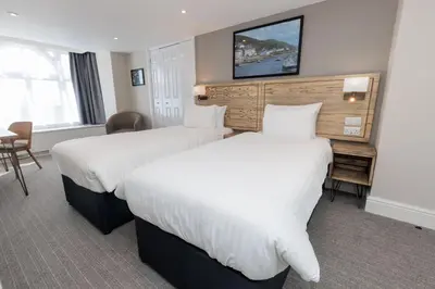 a hotel room with two beds and a tv on the wall at Dovey Inn in Aberdyfi