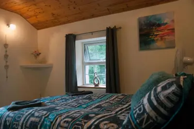 a bedroom with a bed and a window at Hilltop Cottage/ Penrhiw in Maentwrog