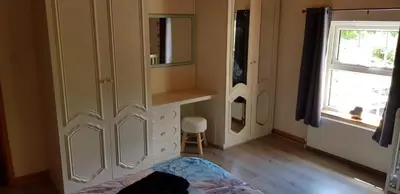 a bedroom with a large white cabinet and a window at Hilltop Cottage/ Penrhiw in Maentwrog
