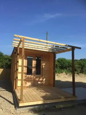 a small building with a roof on a deck at Romantic Getaway Luxury Wooden Cabin With Private Hot Tub and BBQ in Aberystwyth