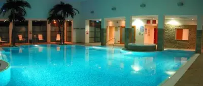 a large blue swimming pool in a building at Burton Hotel in Kington