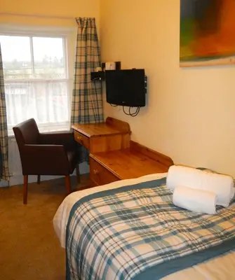 a bedroom with a bed and a desk and a television at Burton Hotel in Kington