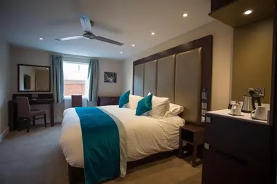 a bedroom with a large bed with a blue blanket at Burton Hotel in Kington