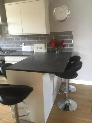 a kitchen with a black counter with stools and a clock at Victorian Church Flat 3 in Oswestry