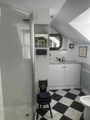 a bathroom with a glass shower and a chair at Tallow House in Ludlow