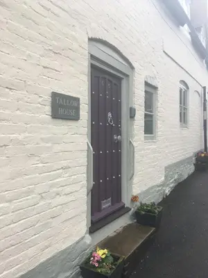 a white building with a door and a sign on it at Tallow House in Ludlow