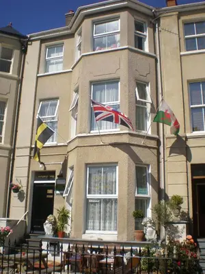 a building with flags flying in front of it at Llwynygog Guest House in Aberystwyth