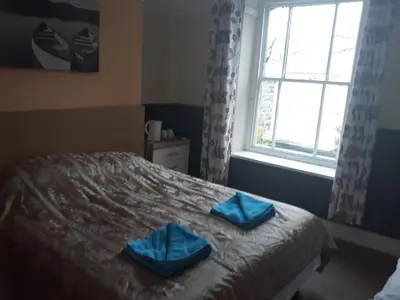 a bedroom with a bed with blue towels on it at Llwynygog Guest House in Aberystwyth