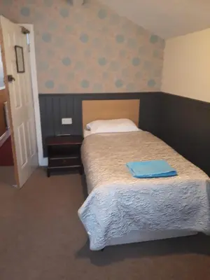 a bedroom with a bed with a blue towel on it at Llwynygog Guest House in Aberystwyth
