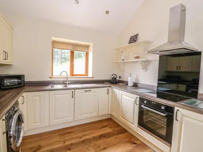 a kitchen with white cabinets and a sink at Pentre Fach in Llanddewi Ystradenny