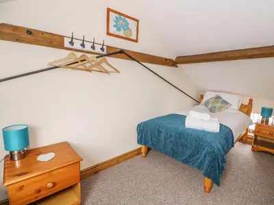 a bedroom with a bed with a blue blanket and a table at Pentre Fach in Llanddewi Ystradenny