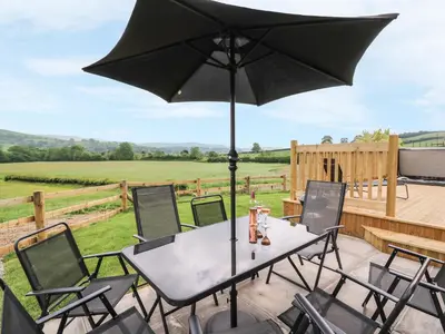 a table and chairs with an umbrella on a patio at Pentre Fawr in Llanddewi Ystradenny