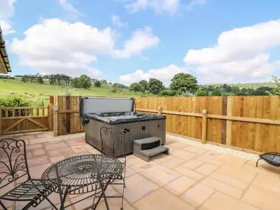 a patio with a grill and chairs and a fence at Tegfan in Rhayader