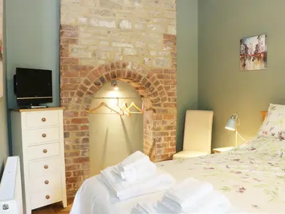 a bedroom with a brick wall with a bed and a tv at Woodpecker Cottage in Ludlow