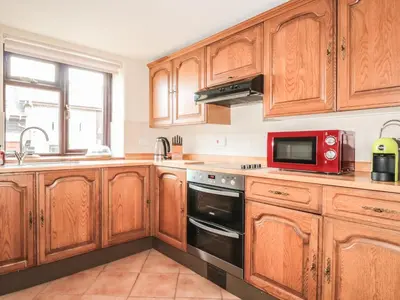 a kitchen with wooden cabinets and a red microwave at The Courtyard in Kington
