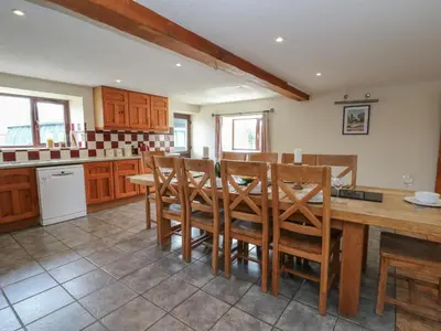 a kitchen with a wooden table and chairs at Glanyrafon in Rhayader