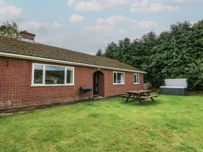a brick house with a picnic table in the yard at Glanyrafon Bungalow in Rhayader