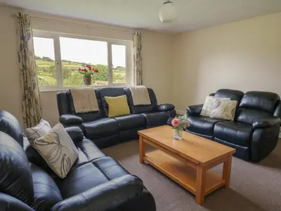 a living room with leather couches and a coffee table at Glanyrafon Bungalow in Rhayader