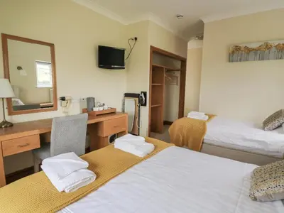 a hotel room with two beds and a desk and a mirror at Llety Ceiro Guesthouse in Aberystwyth