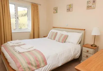 a bedroom with a white bed with two towels on it at Llety Ceiro Guesthouse in Aberystwyth